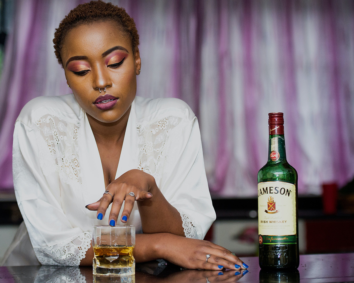 Black woman with a bottle of whisky to medicate burnout